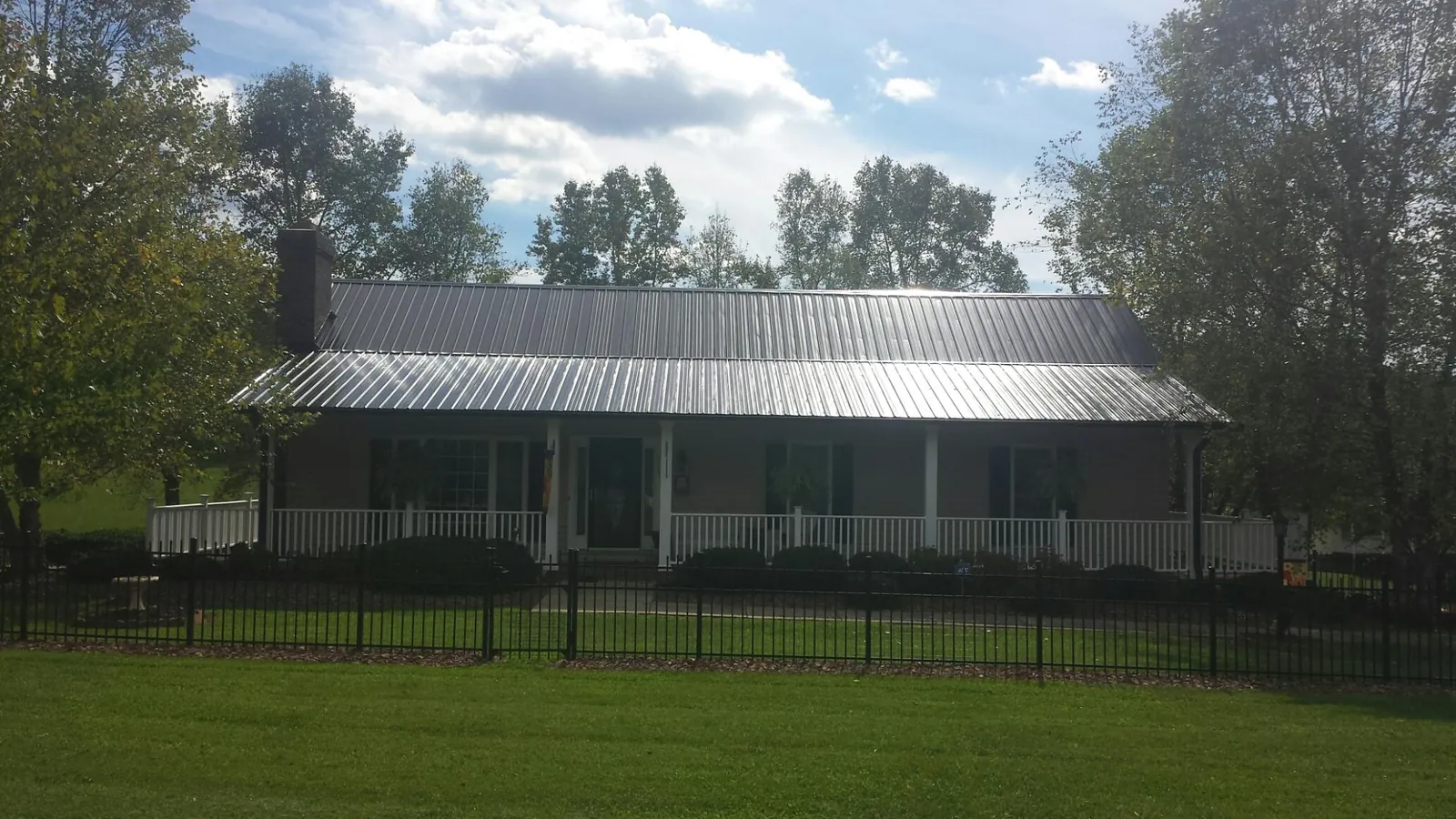 Gray metal roof on a brick ranch with a full width front porch — Gutter Guard Installation work by our crew in Boling